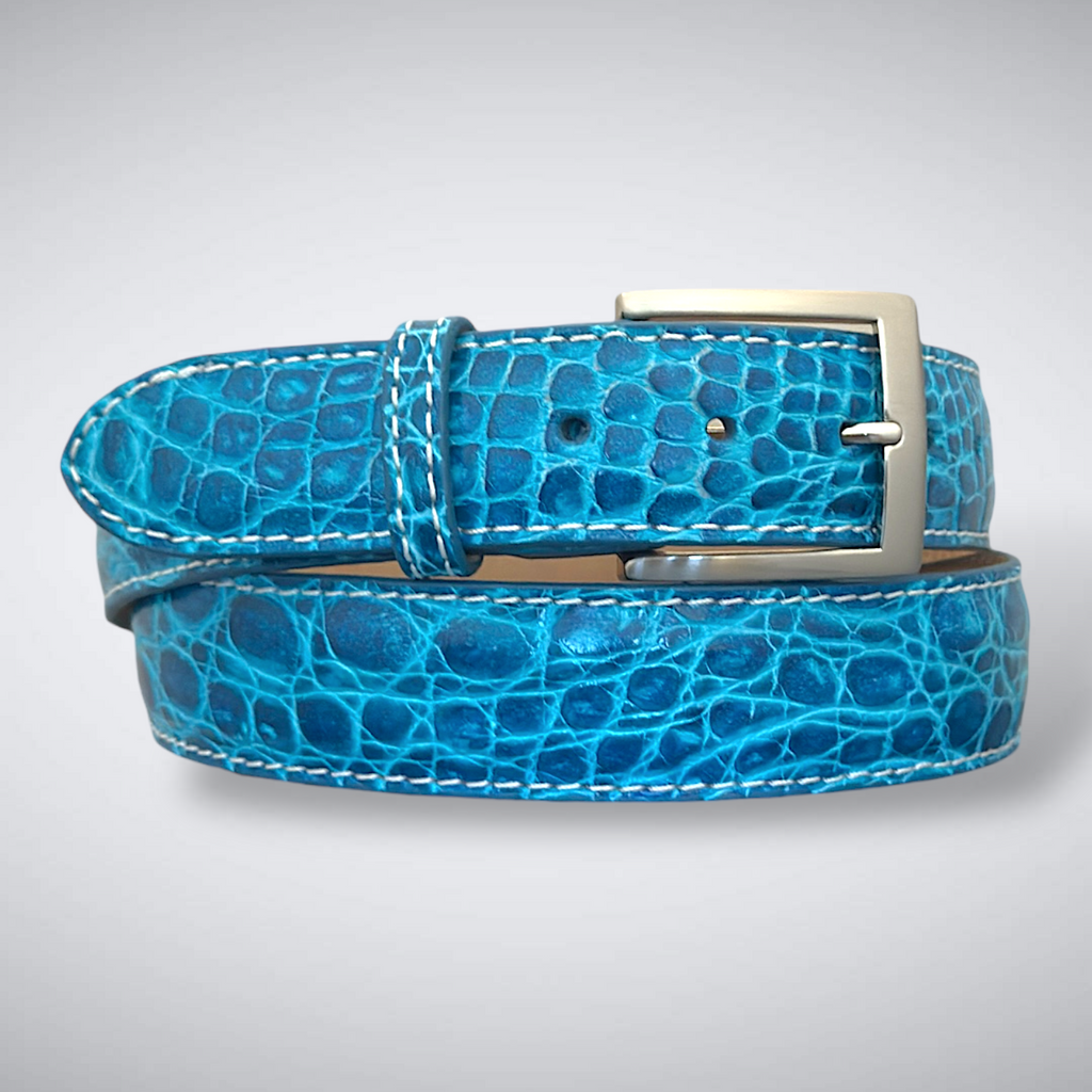 Blue genuine crocodile belt with a silver buckle on a light gray background